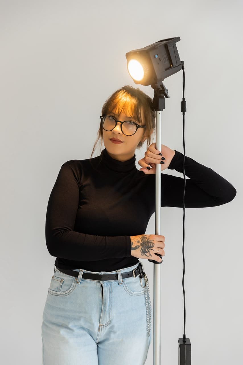Gabriela Clasen em estúdio, ajustando uma luz de cinema.