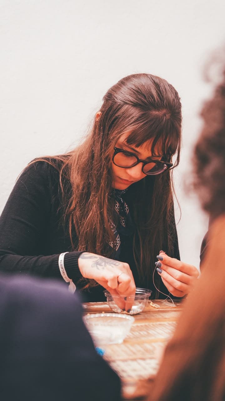 Gabriela Clasen concentrada, trabalhando com as mãos numa oficina.